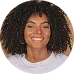 A cheerful woman with curly hair and a bright smile poses confidently, representing the vibrant and diverse player base of KuyaPlay.